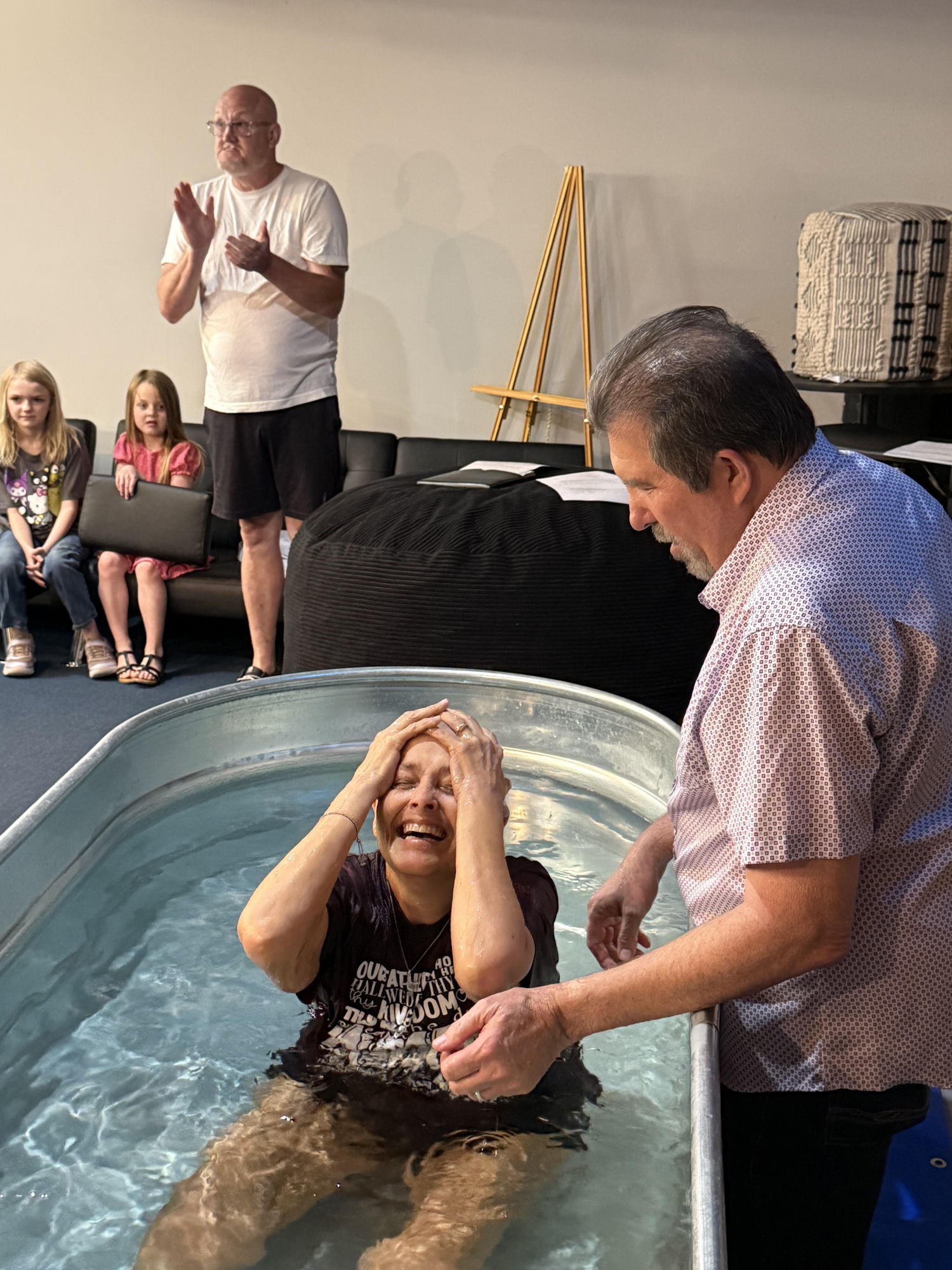 A woman coming up from the water at her baptism, beaming as the church celebrates around her